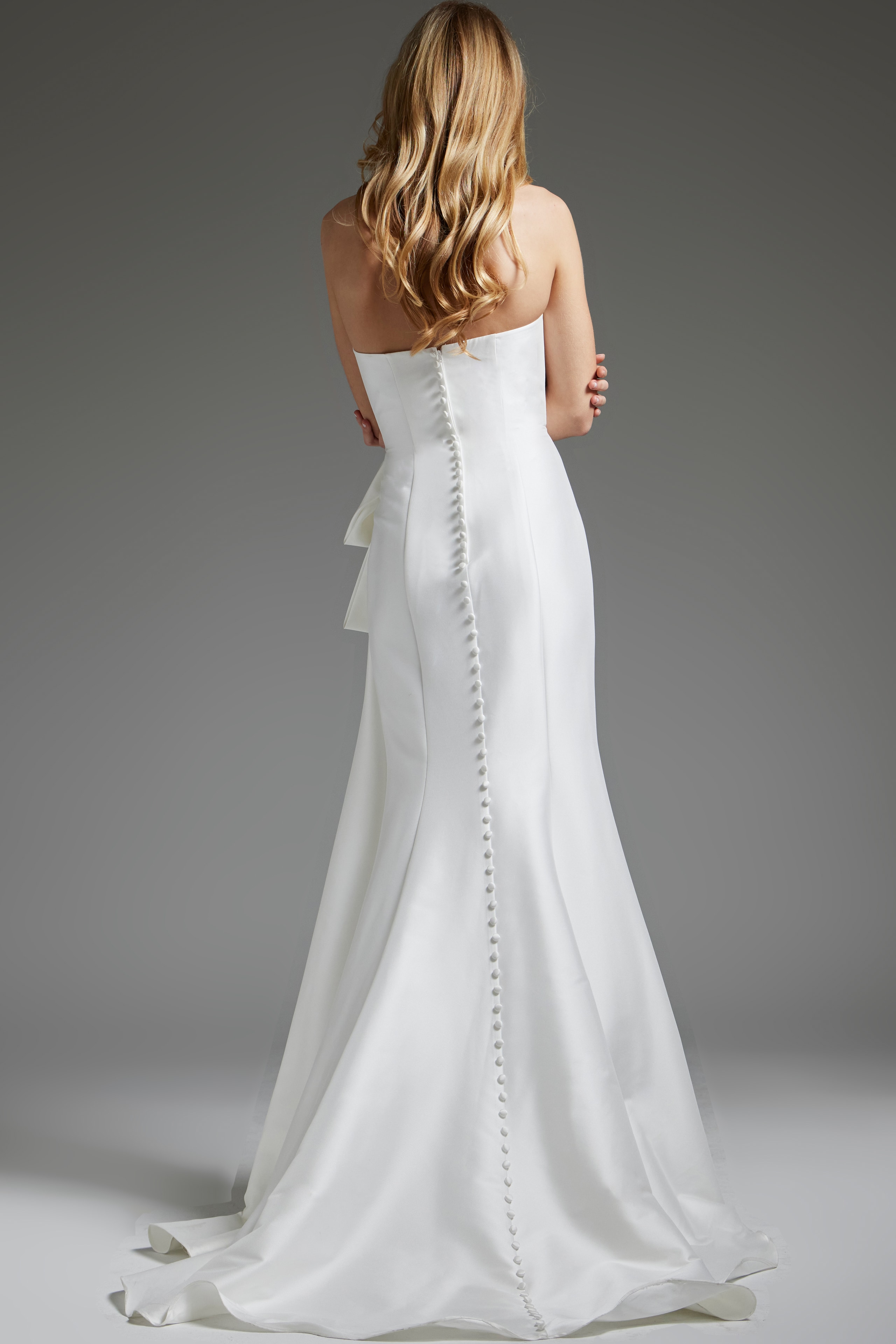 Back view of model in Jovani JB40791 white gown with button detail.