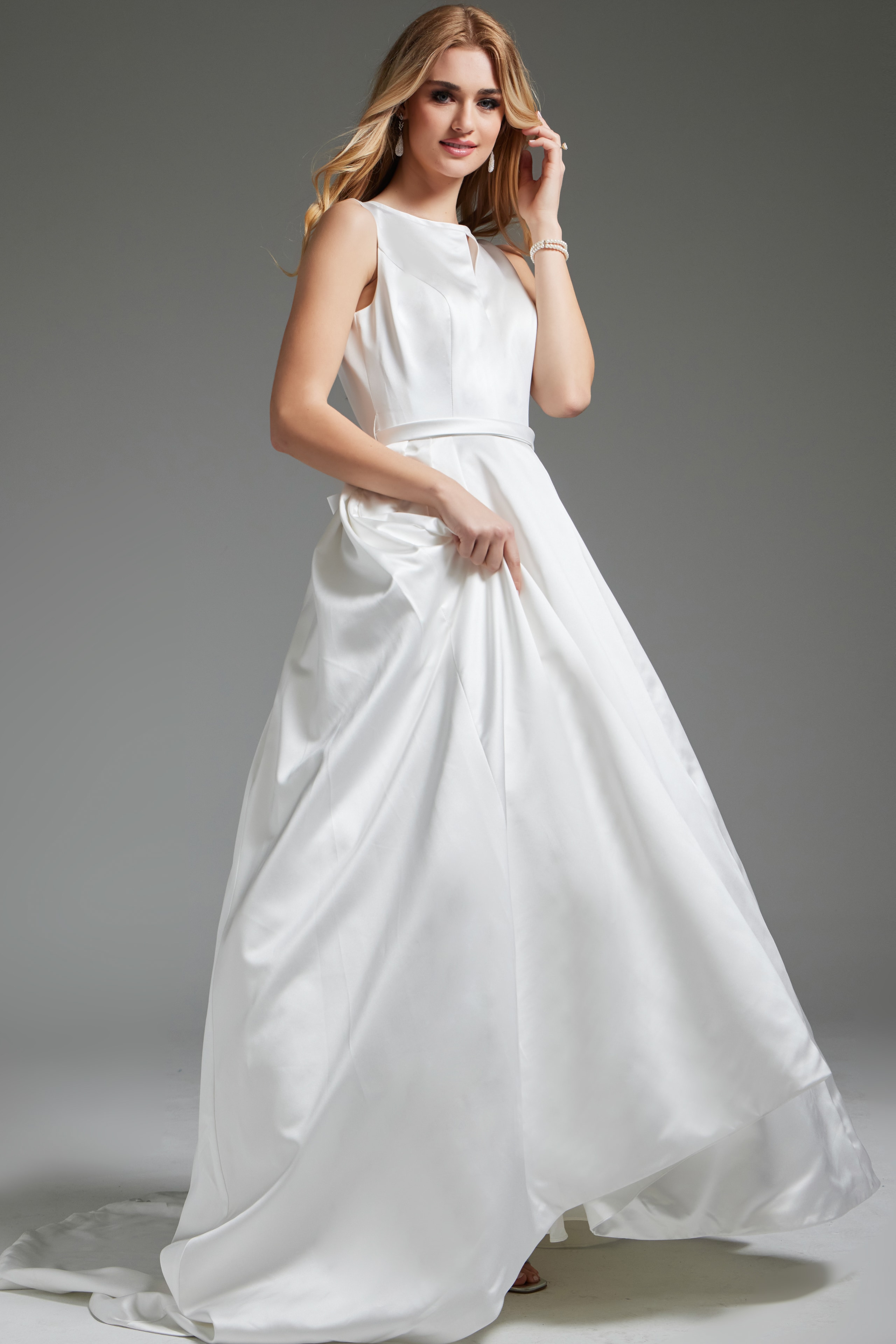 Model in JB42319 ivory gown, front view holding the dress