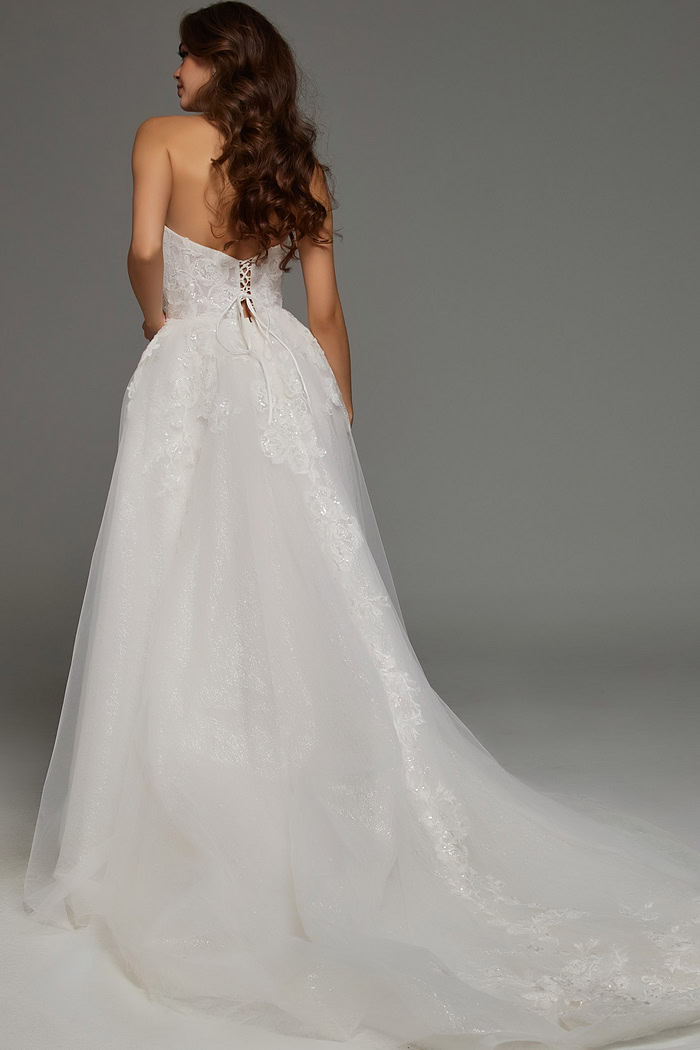 Model wearing Jovani JB43324 ivory dress with lace-up back and cascading train, back view.