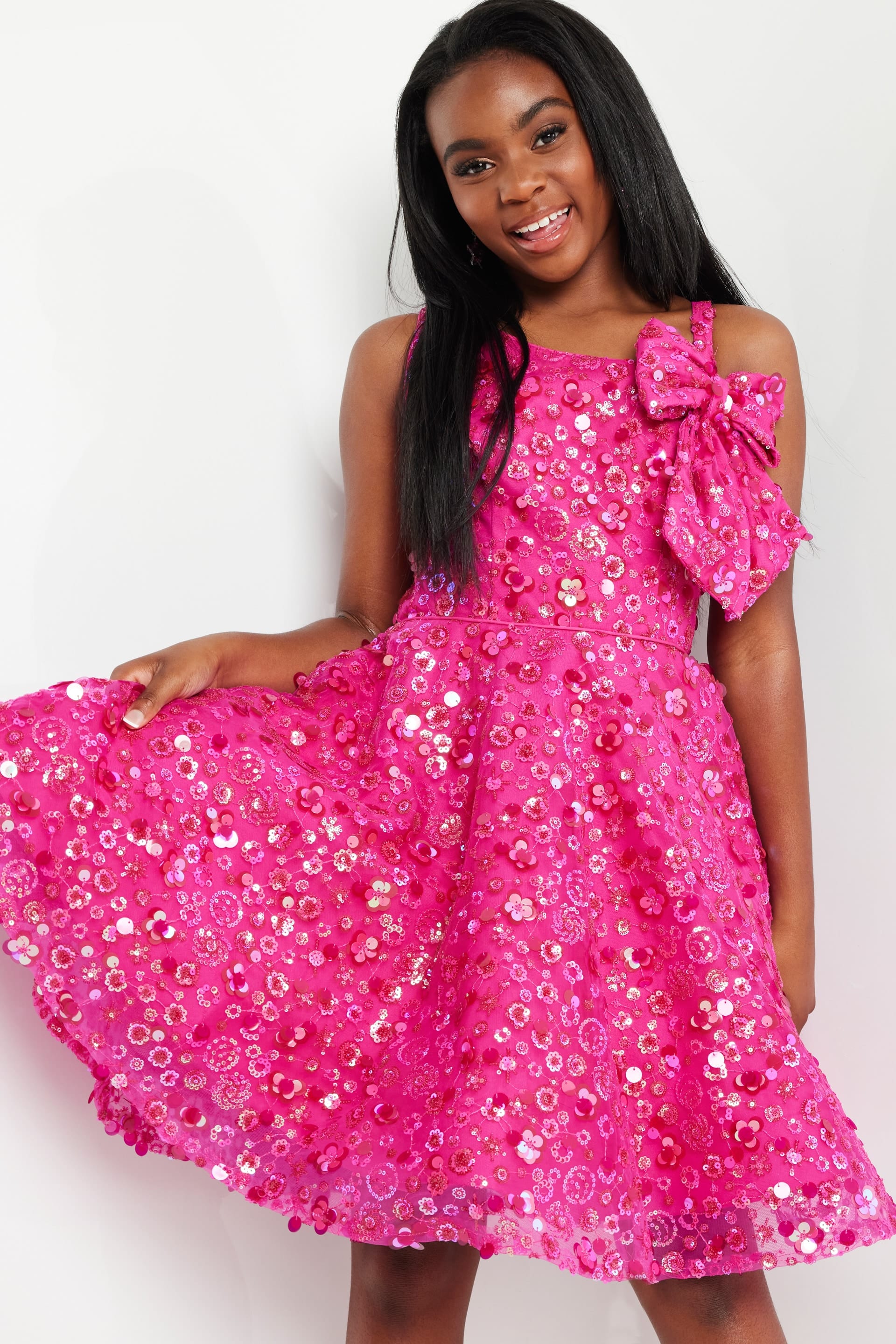 model wearing K23682 fuchsia dress with floral embellishments, front view, holding skirt