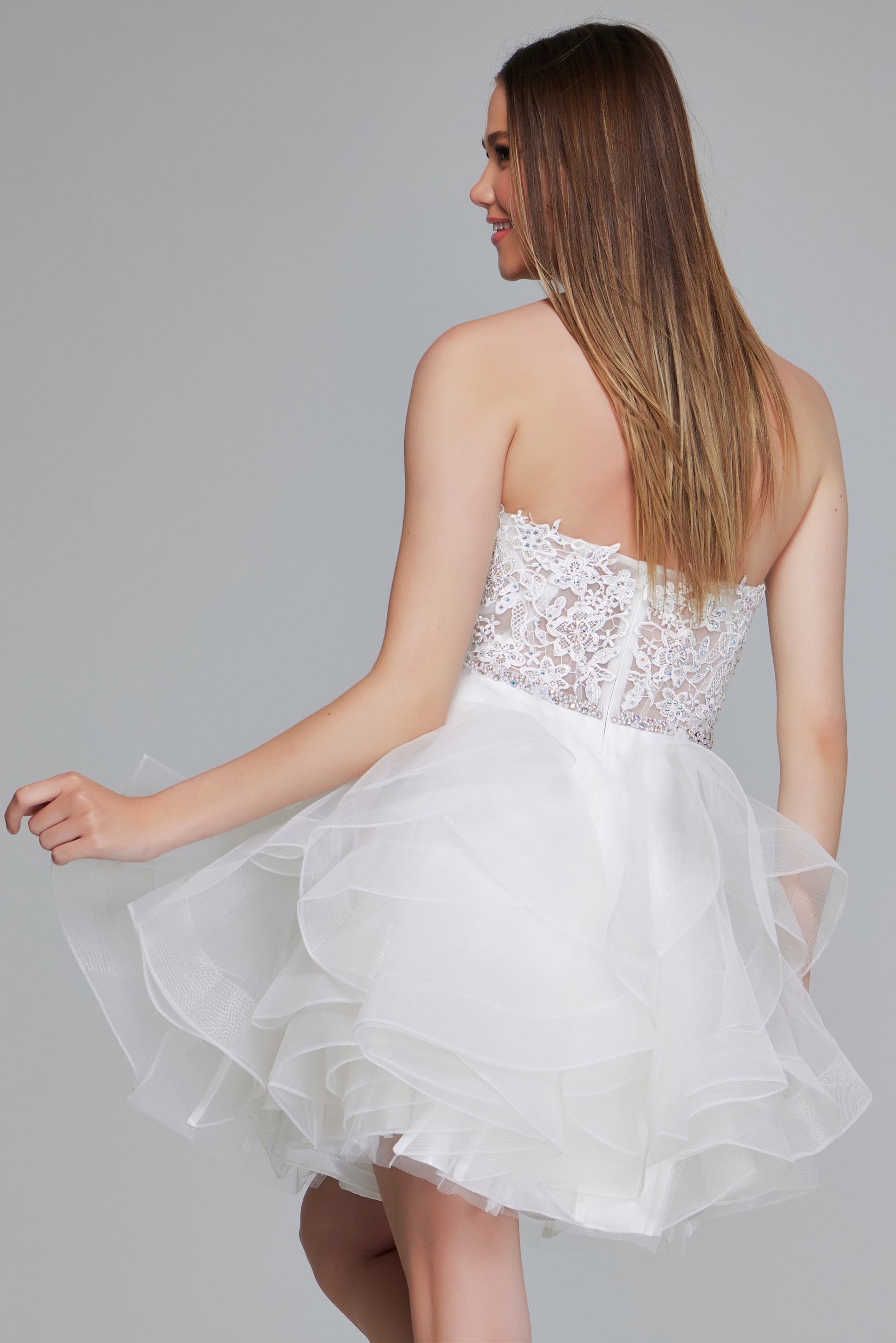 Model wearing Jovani 24371 white dress with intricate lace bodice and tulle skirt, back view.