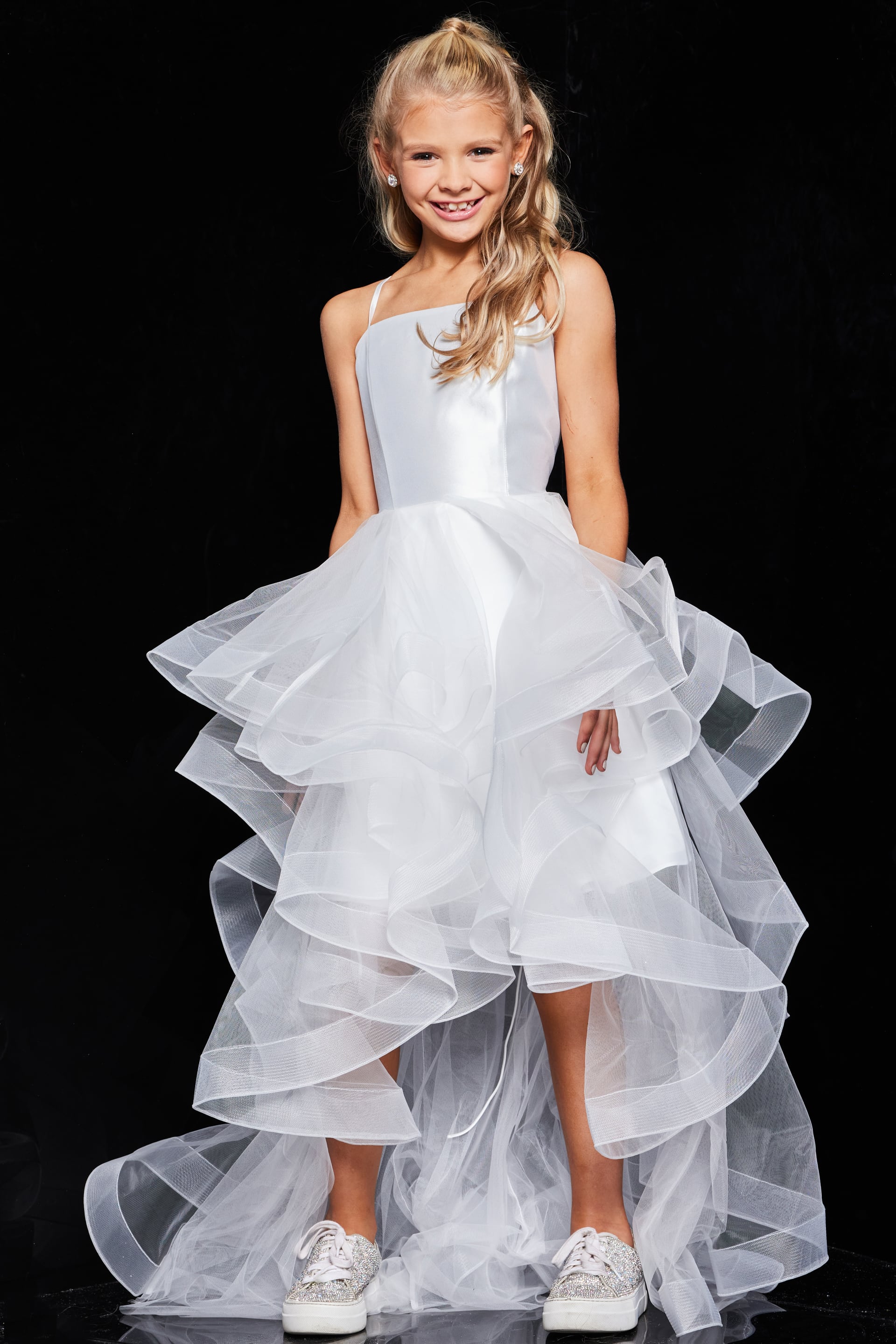 Front view of young model wearing Jovani K66708 white dress with tiered ruffle skirt.