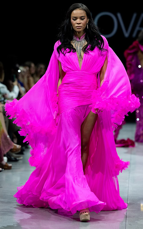 model wearing S36352 vibrant pink gown with plunging neckline and cape sleeves