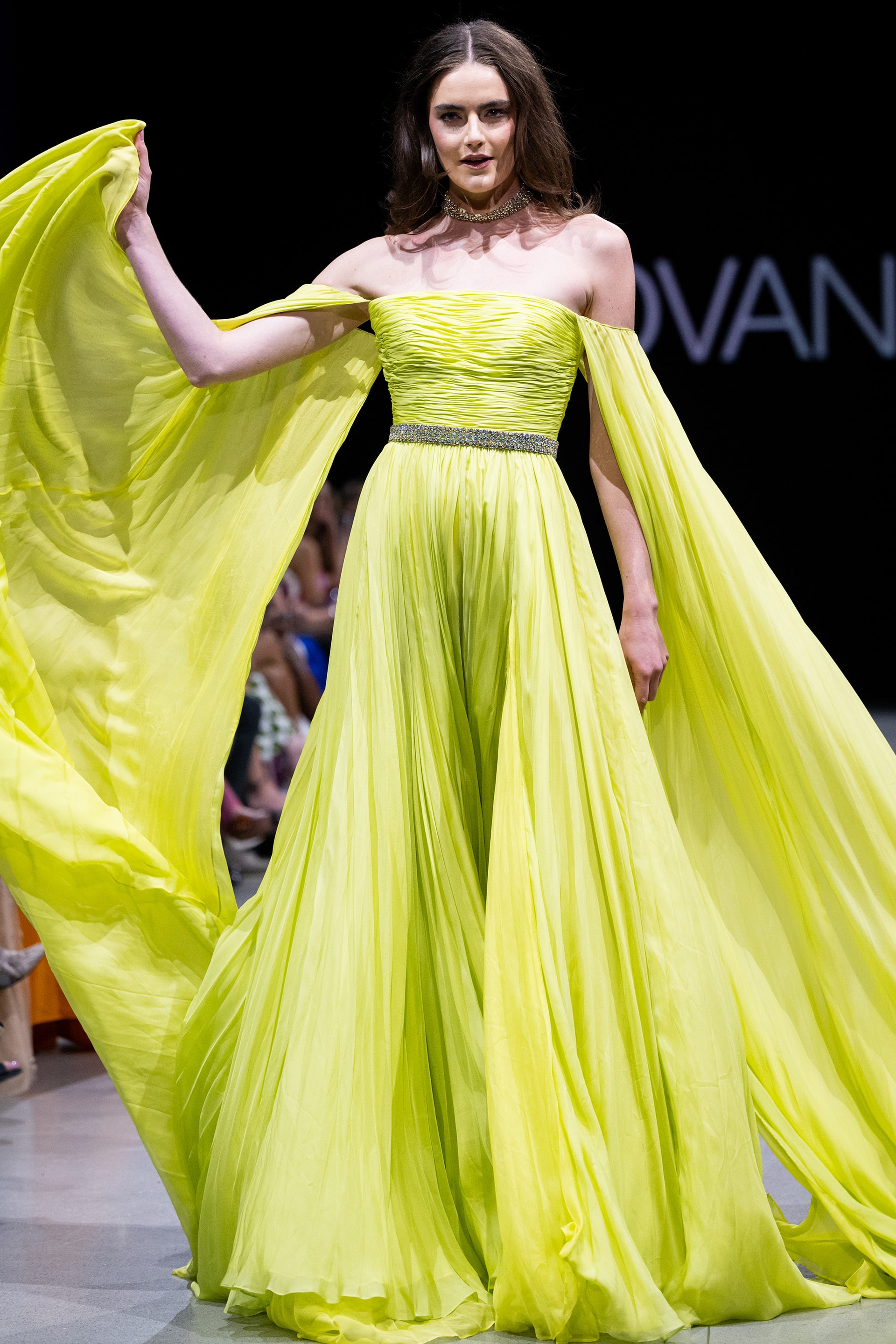 Model wearing Jovani S36443 elegant green gown with off-the-shoulder neckline and flowing sleeves.